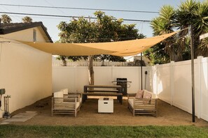 A backyard with a barbecue area, wooden benches, and a canopy.