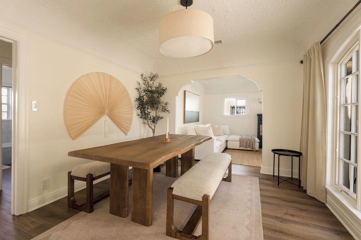 A dining area with a wooden table, benches, and a hanging light fixture.