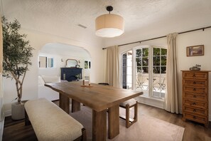 Un comedor con mesa de madera, banco y planta en maceta.