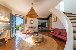 A spacious living area with a red sofa, a woven coffee table, and a hanging light fixture.