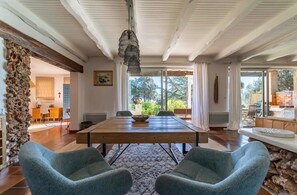 A dining area with a wooden table, two blue chairs, and a hanging light fixture.