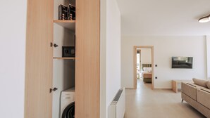 Eine moderne Wohnung mit Waschbereich, einem Wohnzimmer mit einer Couch und einem Flur, der zum Badezimmer führt.