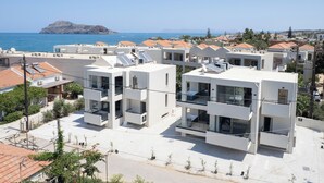 Ein moderner Apartmentkomplex mit mehreren Balkonen, Blick auf das Meer und einer fernen Insel.