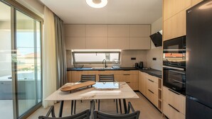 Eine moderne Küche mit Esstisch, Stühlen, einem Kühlschrank und einem Fenster.