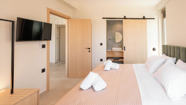 Ein Hotelzimmer mit Bett, Fernseher, Badezimmer mit Spiegel und Kleiderschrank.