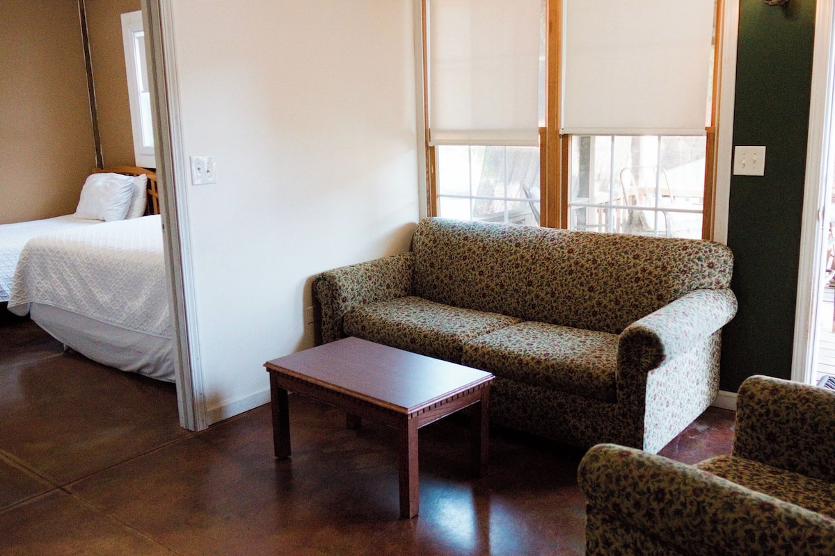 A room with a bed, a sofa, a chair, and a small table.