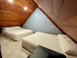 Habitación con dos camas, techo de madera y paredes azul claro.