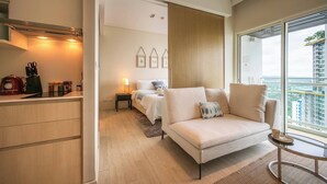 Ein modernes Hotelzimmer mit Küchenzeile, einer Couch, einem Bett und einem Balkon mit Blick auf die Stadt.