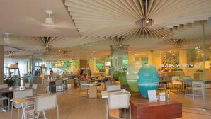 Ein modernes Interieur mit einem einzigartigen Deckenstil, Glastrennwänden und einer zentralen Sitzgruppe mit Tischen und Stühlen.