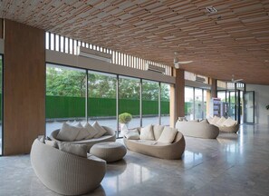 Un hall d’entrée spacieux, doté de meubles modernes, de grandes fenêtres et d’un plafond en bois.