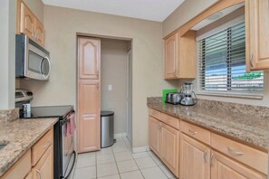 A kitchen with wooden cabinets, a microwave, a toaster, and a window with blinds. - Expanded Saddlebrook 2bed/2bath Condo. Sleeps 8 (Zephyrhills)