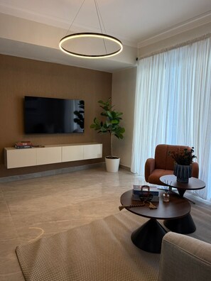 Ein modernes Wohnzimmer mit Flachbildfernseher, Topfpflanze, Sofa, Couchtisch und dekorativer Vase.