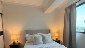 Ein Hotelzimmer mit Bett, zwei Nachttischen, einem Fenster mit Vorhängen und einer Deckenleuchte.