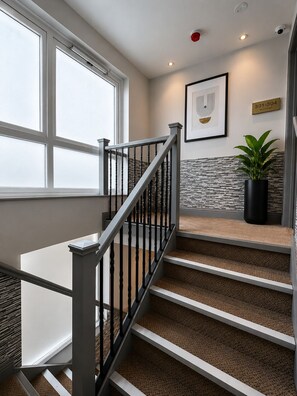 Una escalera con barandilla de metal, una planta en maceta y un letrero en la pared.