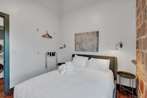 Una habitació d'hotel amb un llit, una barra de tovalloles, una obra d'art penjada a la paret i una taula petita.