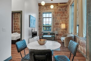Habitació d'hotel moderna amb zona de menjador, una finestra gran amb vistes i una paret de maó.