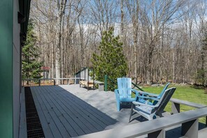 A wooden deck with outdoor seating, a staircase, and a view of a forest. - Charming 3-Bedroom Chalet in Tranquil Mt Holly, VT - Summer or Winter Getaway (Mount Holly)