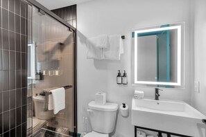 A modern bathroom with a glass shower enclosure, a toilet, a sink with a mirror, and toiletries. - 3 Bedroom Apartment, French Quarter, Central Location, Pool, Walkable (New Orleans)