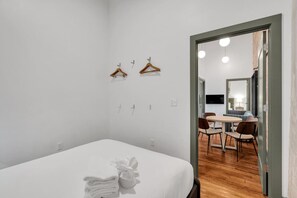 A hotel room with a bed, a dining area with chairs, a table, and a mirror.
