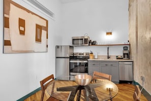 A compact kitchen with a microwave, oven, refrigerator, and a coffee maker.