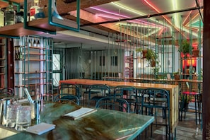 Ein modernes Restaurant-Interieur mit freiliegenden Backsteinwänden, Metallregalen und einer Mischung aus Holz- und Metallmöbeln.