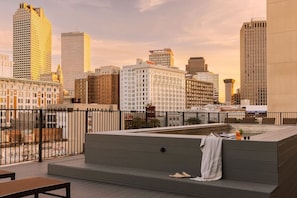 A rooftop terrace with a seating area, a hot tub, and a city skyline view.