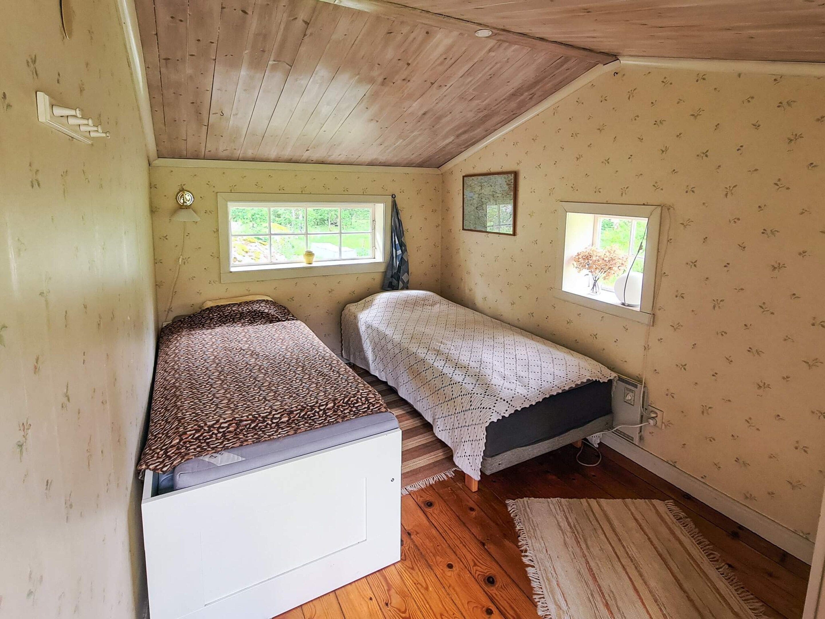 A small bedroom with two beds, a window, and a radiator.