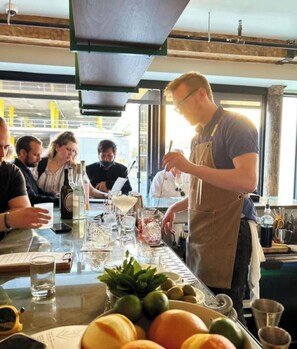 Un espace bar avec un barman préparant des boissons, un menu et une table avec des verres et des bouteilles.