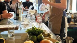 En bardisk där en bartender gör i ordning drinkar, ett bord med glas och flaskor och ett fönster med utsikt.