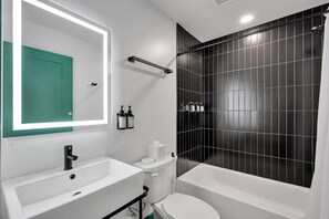 Un bagno moderno con lavandino, vaso e vasca da bagno bianchi.