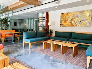 Un salon moderne avec un ensemble de canapés, des tables basses en bois et un grand tableau abstrait accroché au mur.