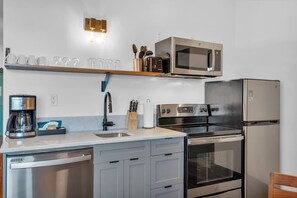 A modern kitchen with a dishwasher, stove, microwave, and refrigerator.