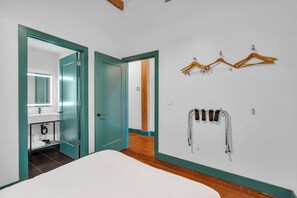A bedroom with a bed, a bathroom with a mirror, and a wall-mounted towel rack.