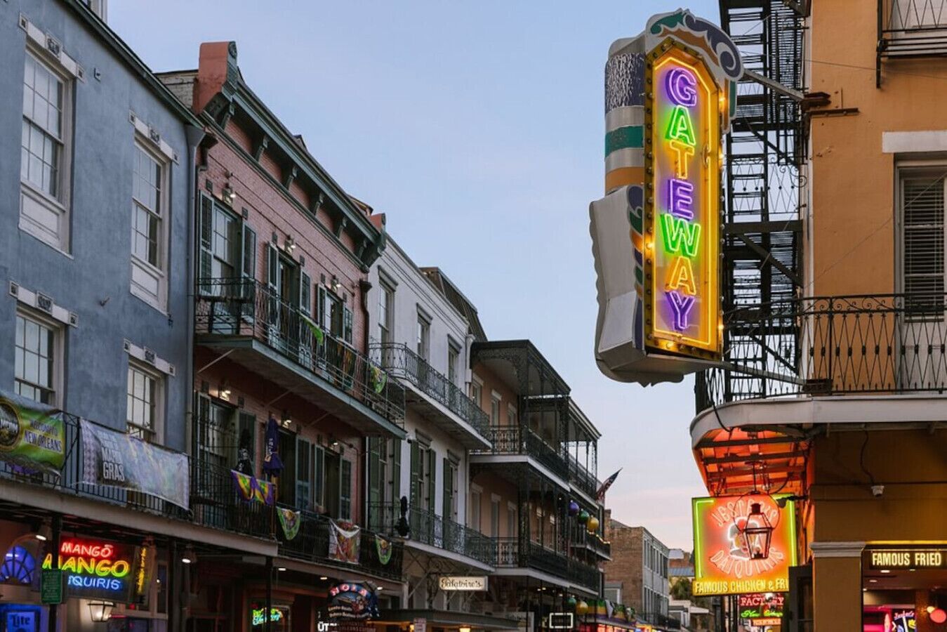 A street view with a neon 'GATEWAY' sign, buildings with balconies, and various storefronts including a famous fried chicken restaurant.
