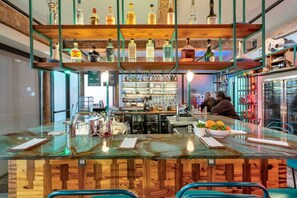 A bar area with a wooden counter, shelves with bottles, and a menu board.