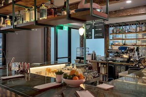 Uma área de bar com balcão, prateleiras com garrafas, um quadro de menu e um sinal de saída.