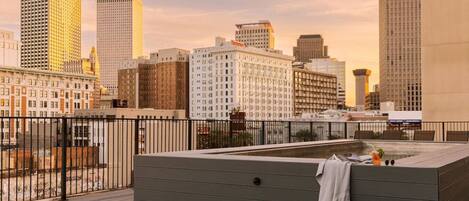 A rooftop terrace with a seating area, a hot tub, and a city skyline view.