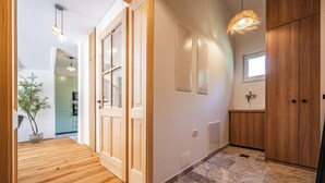 Un couloir doté d’un plancher en bois, d’une plante en pot et d’une porte donnant sur une pièce avec une fenêtre.