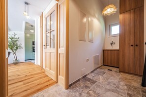 Ein Flur mit Holzboden, einem Blumentopf und einer Tür zu einem Zimmer mit Fenster.