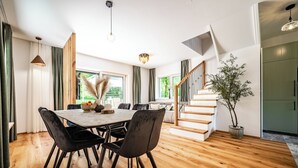 Un espace repas moderne avec une table et des chaises en bois, un escalier et une plante en pot.