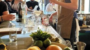 Eine Bar mit einem Barkeeper, der Getränke zubereitet, einer Speisekarte und einer Auswahl an Flaschen und Gläsern hinter der Theke.