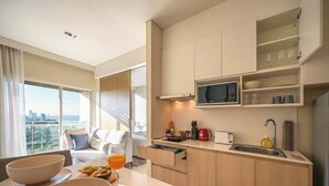 A modern kitchen with a microwave, sink, and dining area. - King Bed Sea View Condo | 2 Resort Pools | 1min to Private Beach (Sattahip)