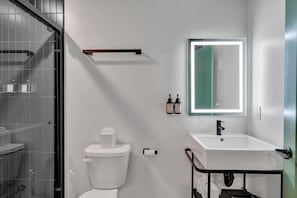 Uma casa de banho moderna com sanita, lavatório e espelho.