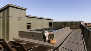 A rooftop terrace with a swimming pool, lounge chairs, and a small building structure.