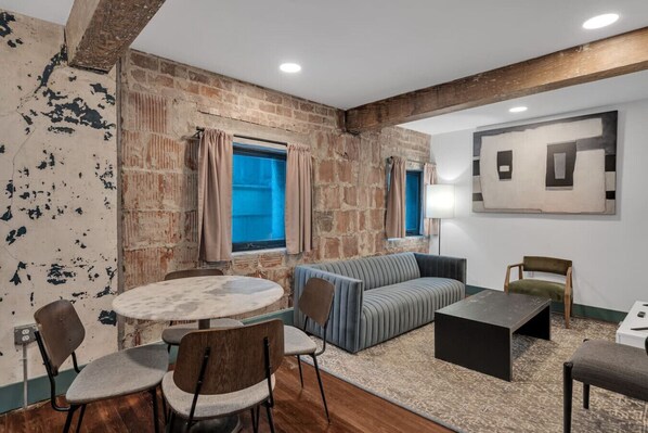 Una habitación con pared de ladrillo, una mesa redonda, un sofá y una lámpara.