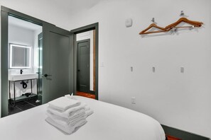 A hotel room with a bed, a bathroom with a mirror, a sink, and a wall-mounted towel rack.
