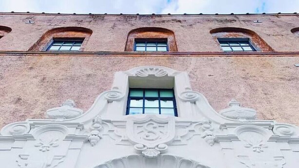 A building with a large arched window and the name 'SCHAEFFER' illuminated on the facade.