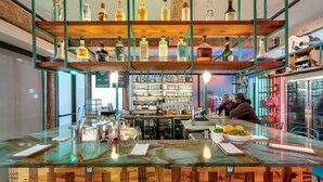 A bar area with a wooden counter, shelves with bottles, and a menu board.