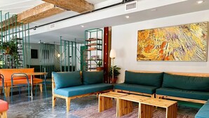 A modern living room with a sofa set, wooden coffee tables, and a large abstract painting on the wall.