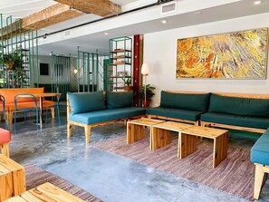 Uma sala de estar moderna com um conjunto de sofá, mesas de centro de madeira e uma grande pintura abstrata na parede.
